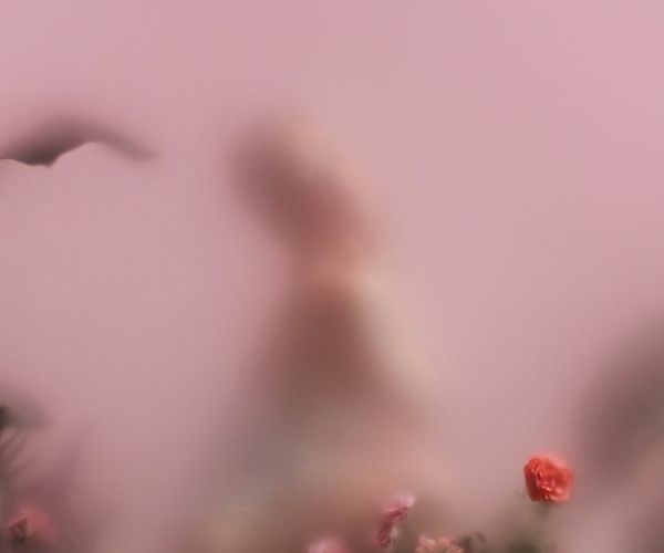 Person meditating peacefully with a soft pink background glow.